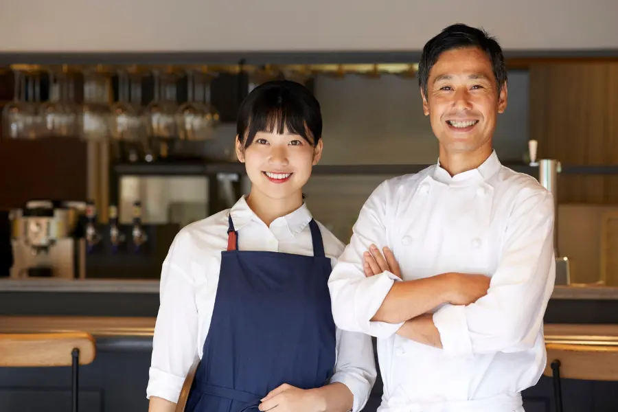 2 chefs smilling at the camera.