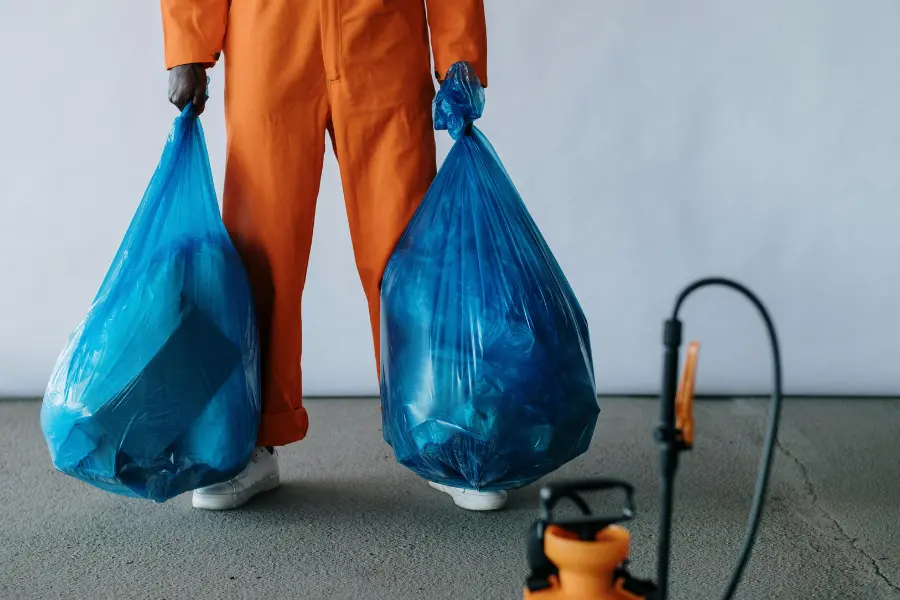 man holding 2 bags of waste