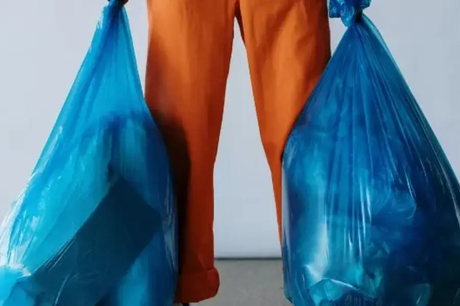 View of a person holding  trash bags for waste management.