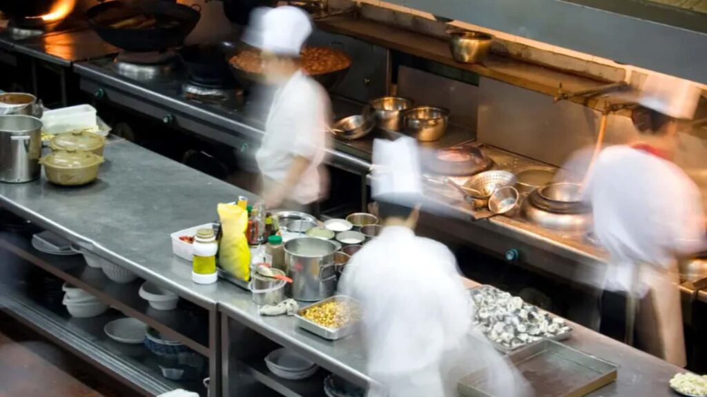 Hospitality kitchen staff coordinating food preparation and service to improve efficiency and reduce delays.
